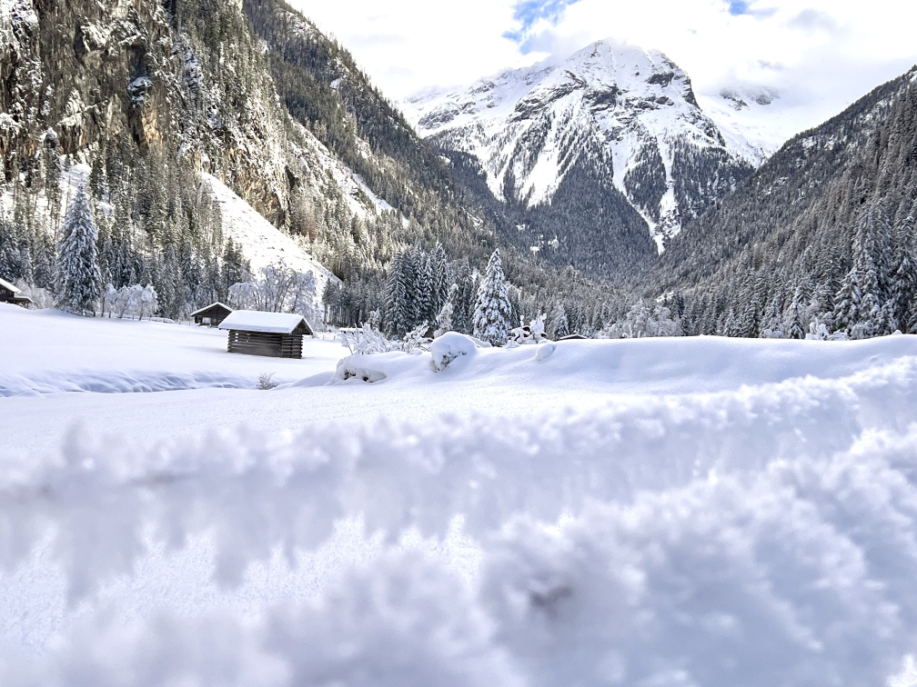 Ein schneebedecktes Feld mit einer Hütte im Hintergrund während einer Winterwanderung in Bad Gastein.