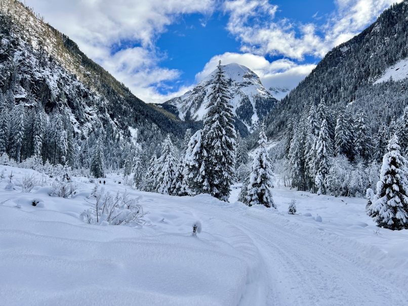 Ein Winterwanderweg im Kötschachtal in Bad Gastein, mit schneebedeckten Bergen und strahlend blauem Himmel.
