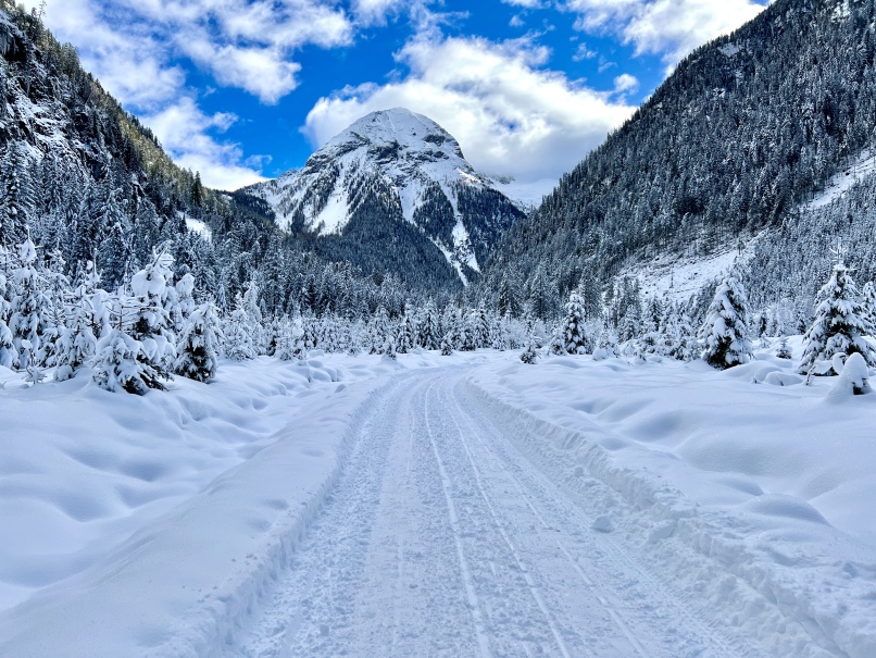Eine verschneite Straße mit Bergen im Kötschachtal, perfekt für eine unvergessliche Winterwanderung in Bad Gastein.