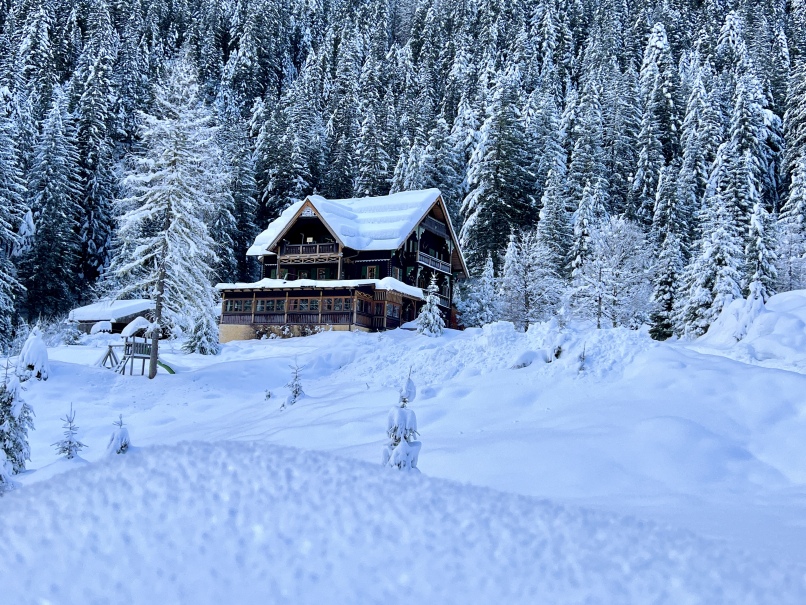 Eine gemütliche Hütte im Kötschachtaler Wald, umgeben von einer weißen Schneedecke.