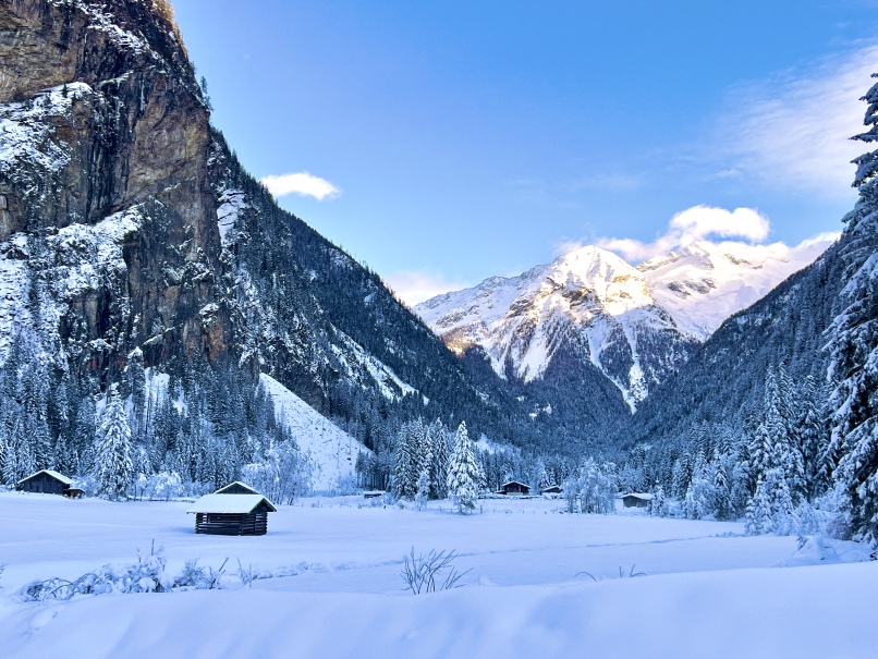 Eine Winterszene in Bad Gastein mit schneebedeckten Bergen und Hütten im Kötschachtal.