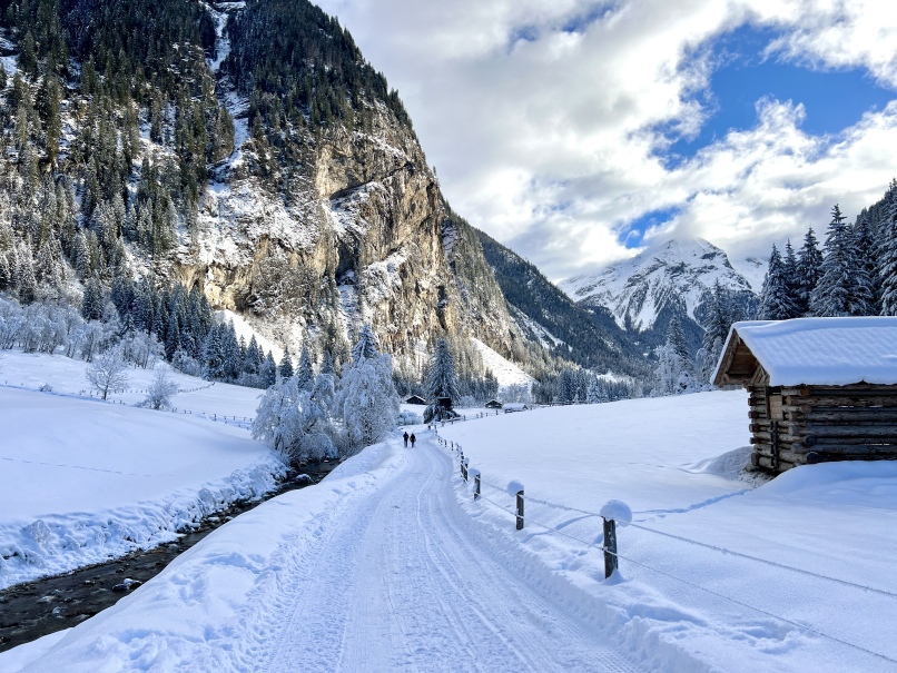 Eine Winterwanderung entlang eines verschneiten Weges im Kötschachtal, der zu einer gemütlichen Hütte in den Bergen von Bad Gastein führt.
